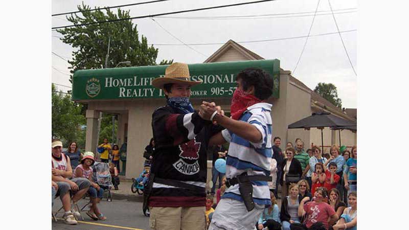 Stage Hypnosis Show 1, Hypnotist Hamilton, Two teenage boys wearing cowboy hats, dual holsters and handkerchiefs over their face dance together romantically after having a gun fight. Taken in Hamilton Ontario
